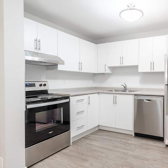 a modern kitchen with stainless steel appliances and white cabinets.