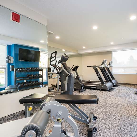 a gym with cardio equipment and a flat screen tv