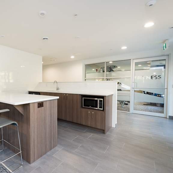 resident lounge white countertops and a wooden island with three red chairs