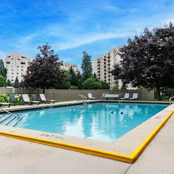 a swimming pool surrounded by trees and chairs.
