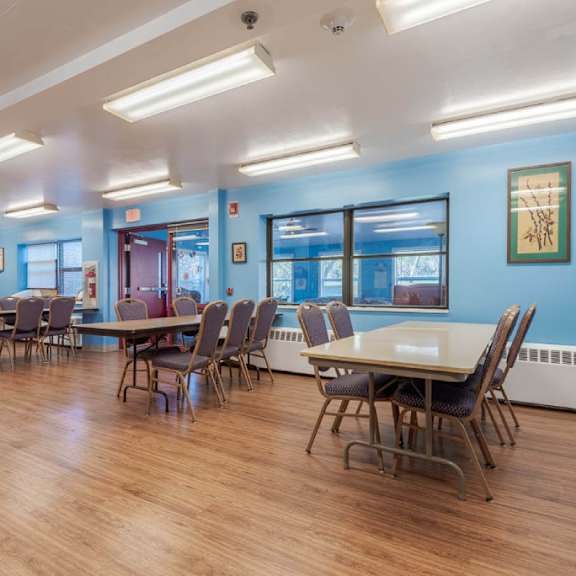 a room with blue walls and wooden floors has tables and chairs.