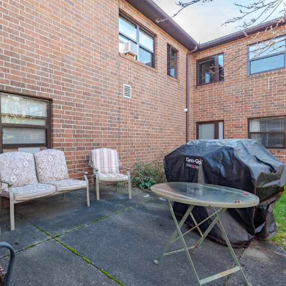 a patio with a table, chairs, and a grill.