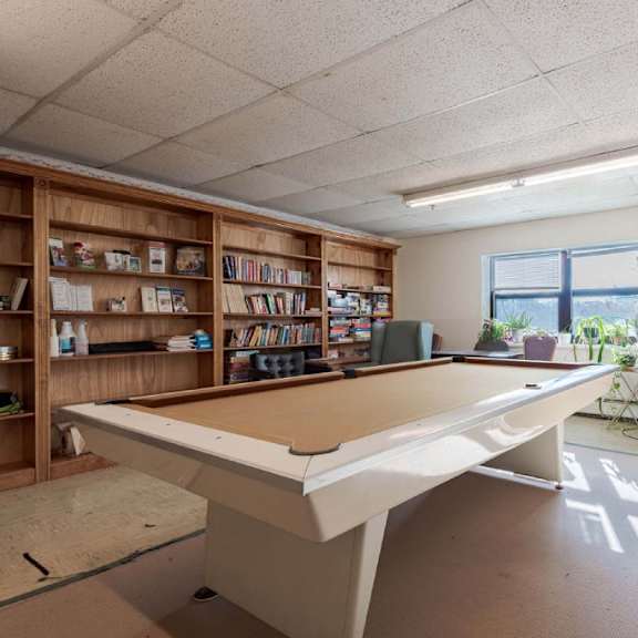 a room with a pool table, bookshelves, and exercise equipment.