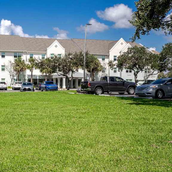 a white building with a green lawn in front.