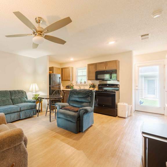 a living room with a ceiling fan and a green couch.