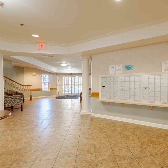 a white board with blue labels is mounted on a wall in a room with tiled floors and a staircase.