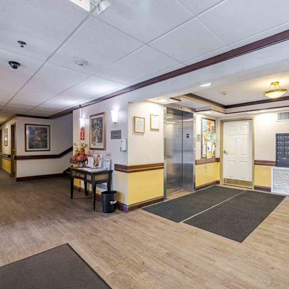 a hallway with a bench, a table, and a calendar on the wall.