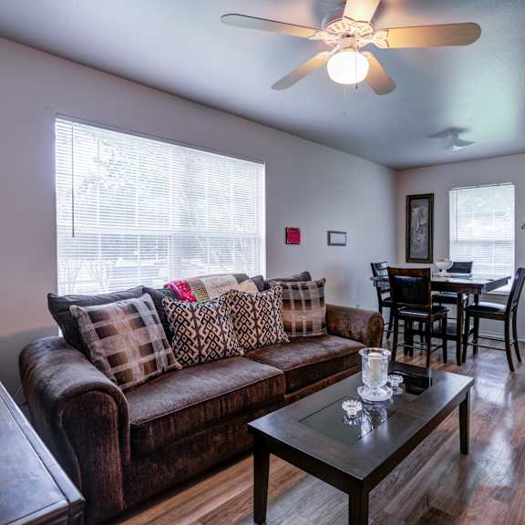 a living room with a brown couch and a ceiling fan.