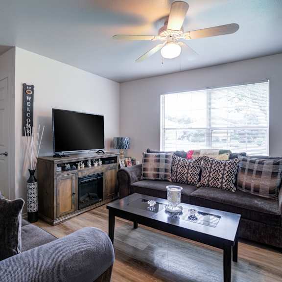 a living room with a grey couch, a black coffee table, and a wooden entertainment center.