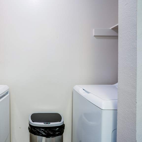 a small bathroom with a toilet, a washing machine and a dryer.