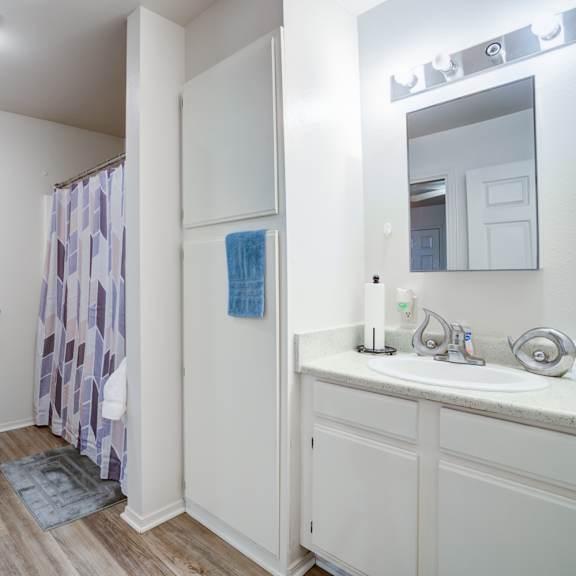 a white bathroom with a toilet, sink, and shower curtain.