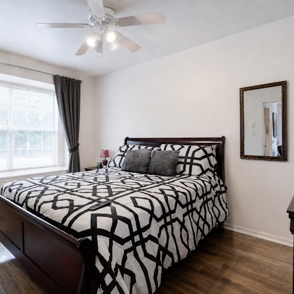 a bedroom with a patterned bedspread and a ceiling fan.