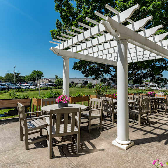 a white pergola with a table and chairs underneath it.