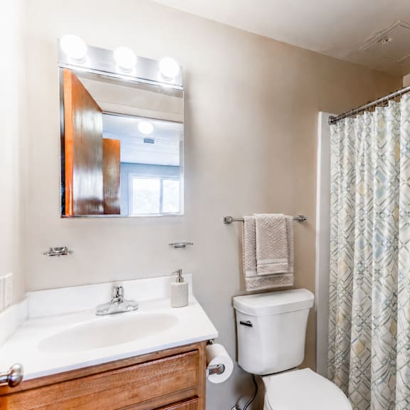 a bathroom with a white toilet, sink, and shower curtain.