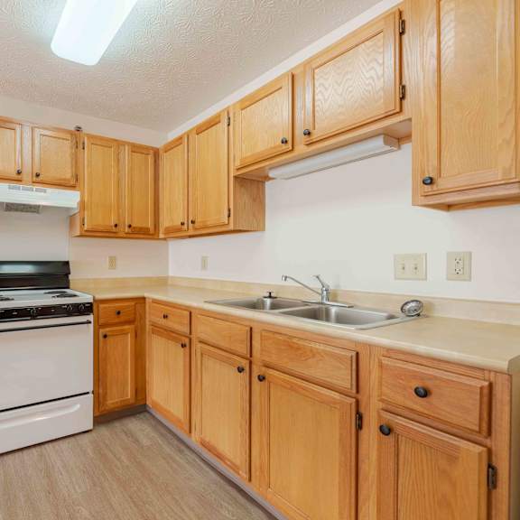 a kitchen with wooden cabinets and a white stove top oven.