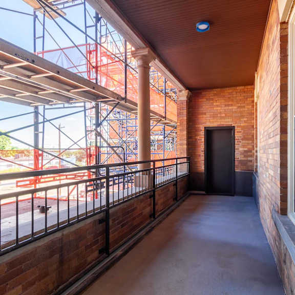 a balcony with a black railing and a brick wall.