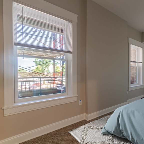 a bedroom with a bed, nightstand, and window with blinds.