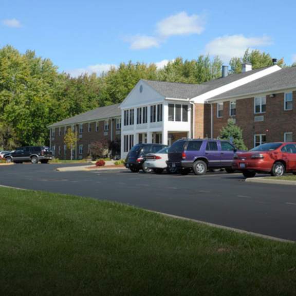 a parking lot in front of a building with cars parked.