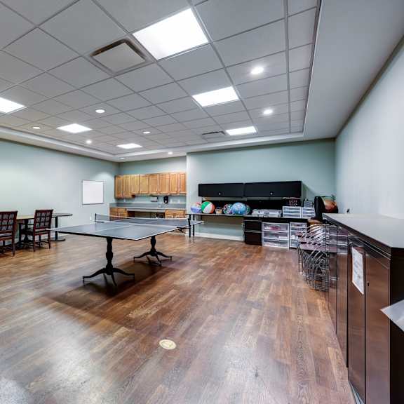 a room with wooden floors and a kitchen area with a refrigerator.