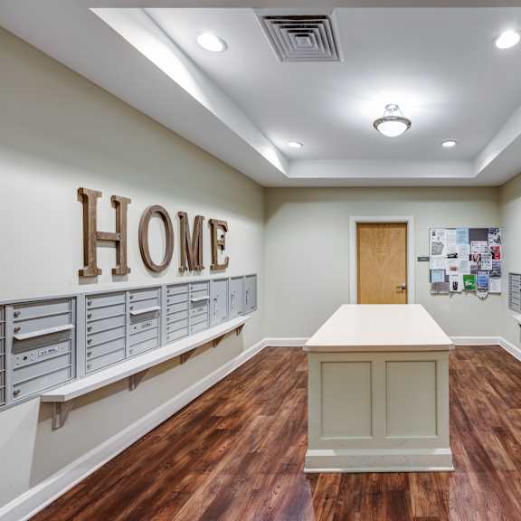 a room with a wooden floor and a large wooden home sign on the wall.
