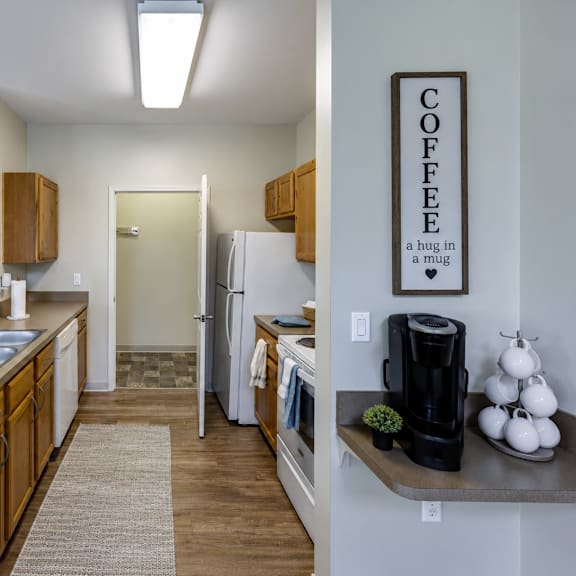 a kitchen with a refrigerator, sink, and a coffee sign on the wall.