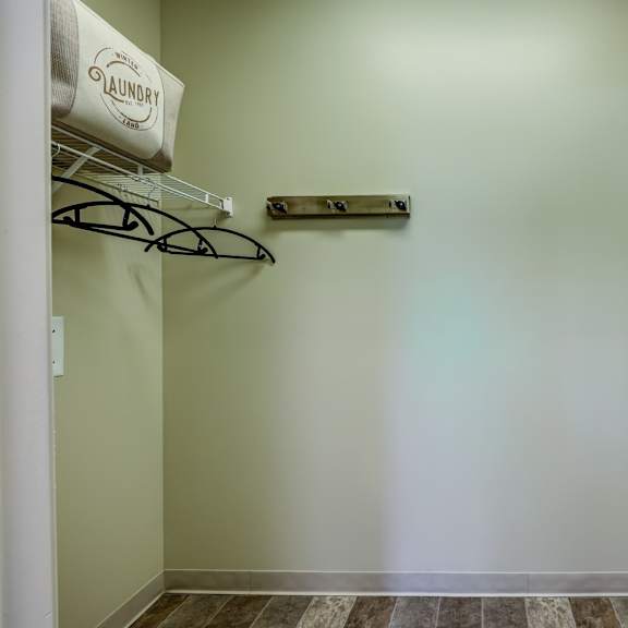 a laundry sign hangs on a wall next to a shelf and a picture frame.
