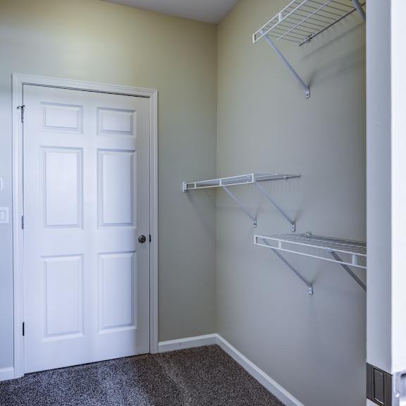 a white door is in the middle of a room with two shelves on either side.