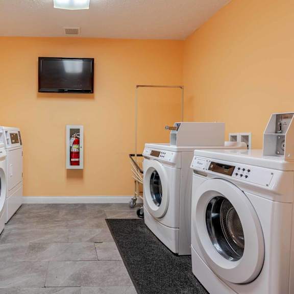 a laundry room with a row of washing machines and a red chair.
