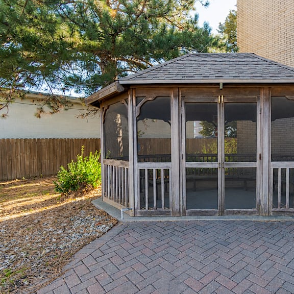 a gazebo with a brick walkway in front of a building.