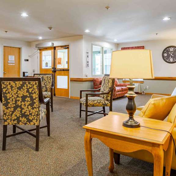 a living room with a yellow sofa, wooden coffee table, and patterned chairs.