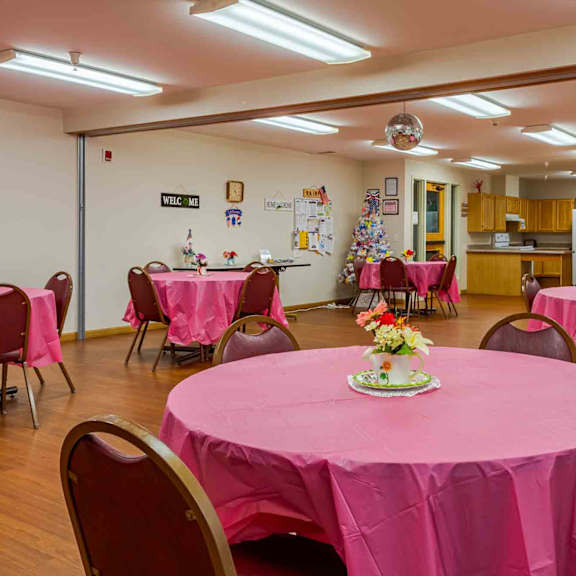a room with tables covered in pink tablecloths and chairs.