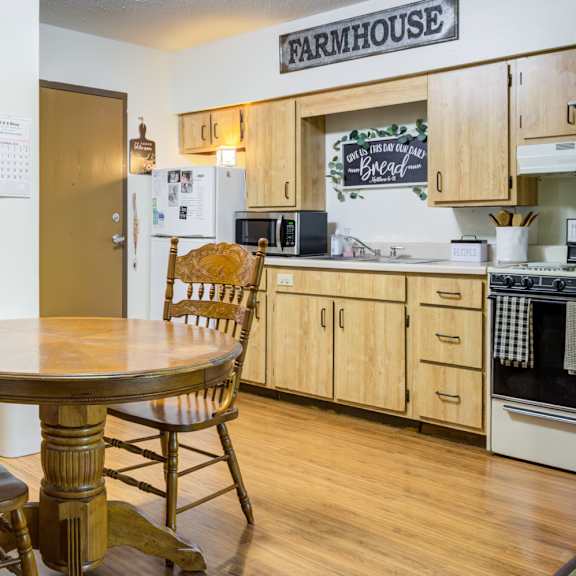 a kitchen with a table and chairs in front of a refrigerator.