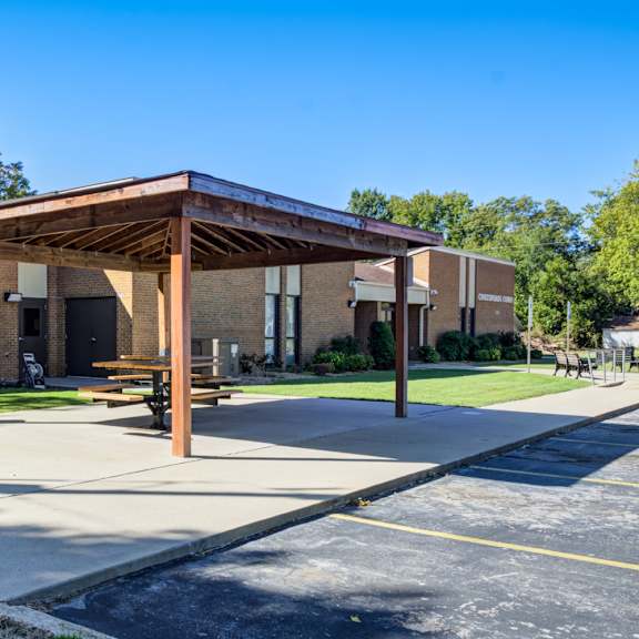 a covered walkway leads to a building with a brick facade.