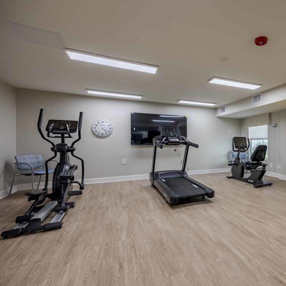 a spacious gym with a variety of equipment including treadmills, exercise bikes, and weights.