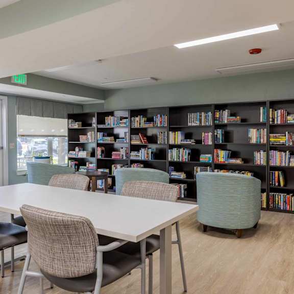 a room with a white table and chairs and a bookshelf filled with books.
