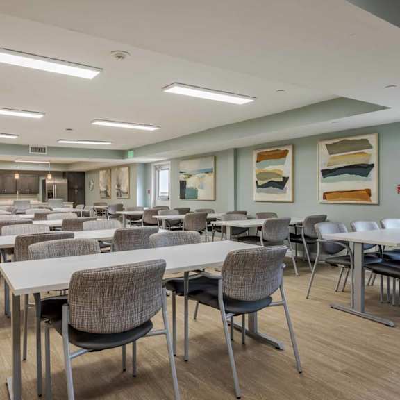 a large room with tables and chairs and a kitchen area.