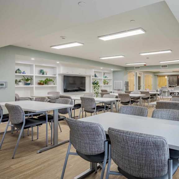 a modern dining room with grey chairs and tables.