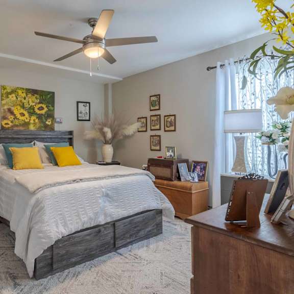 a bedroom with a bed, chair, and ceiling fan.