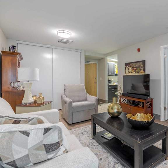 a living room with a grey couch, a coffee table, and a fireplace.