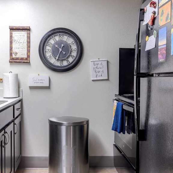 a kitchen with a black fridge and a clock on the wall.