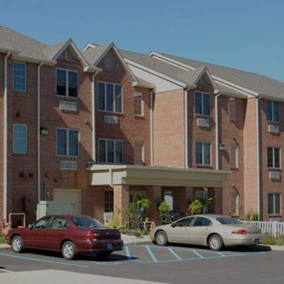 a red car is parked in front of a brick building.