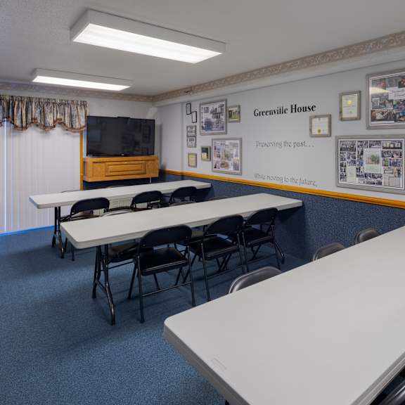 a room with tables and chairs and a wall with certificates on it.
