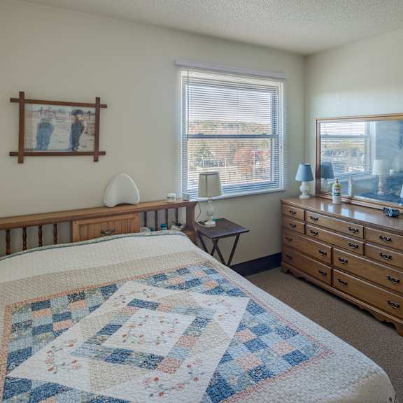 a bedroom with a bed, dresser, and chair.