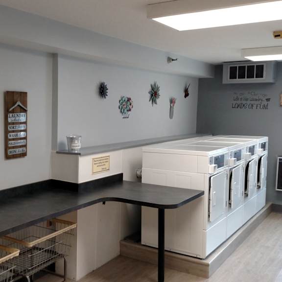 a laundry room with a washer and dryer, a clock, and a table.