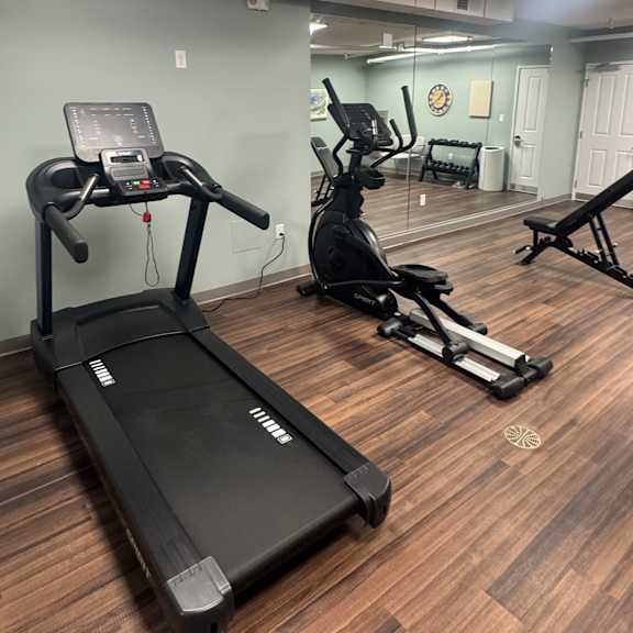 a treadmill and a stationary bike are in a gym.