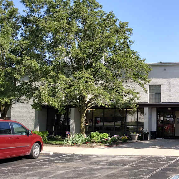 a parking lot with a red car and a building in the background.