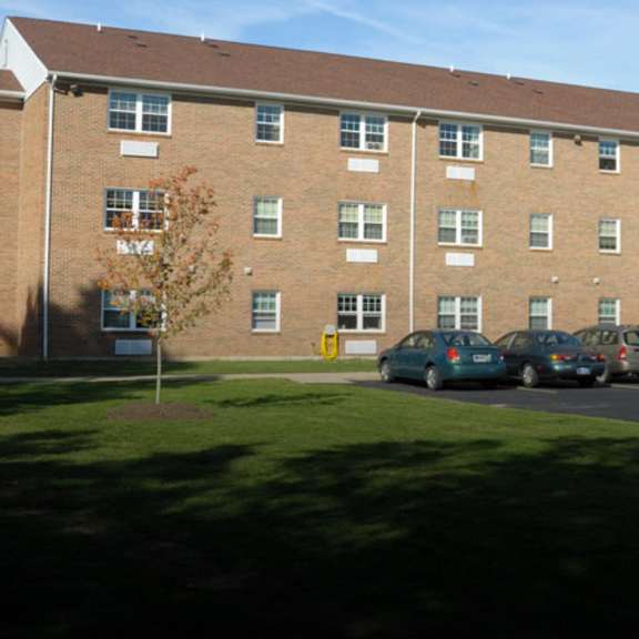 a large brick building with a parking lot in front.