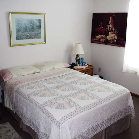 a bed with a white comforter and a picture on the wall.