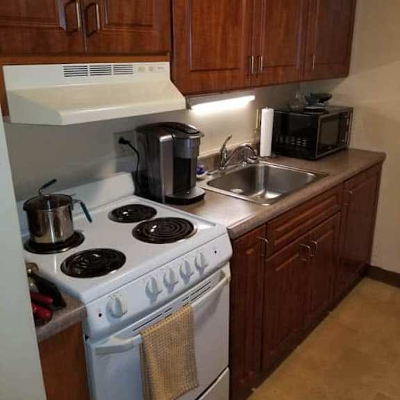 a kitchen with a white stove top and wooden cabinets.
