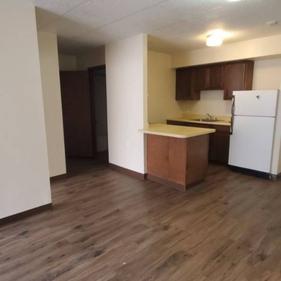 a kitchen with white appliances and wooden floors.